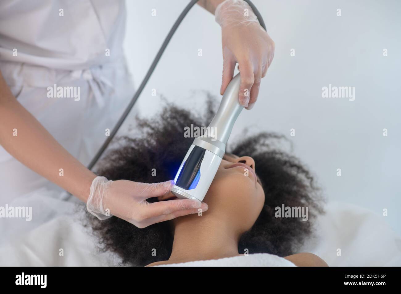 Doctor hands with cosmetic apparatus near patient face Stock Photo
