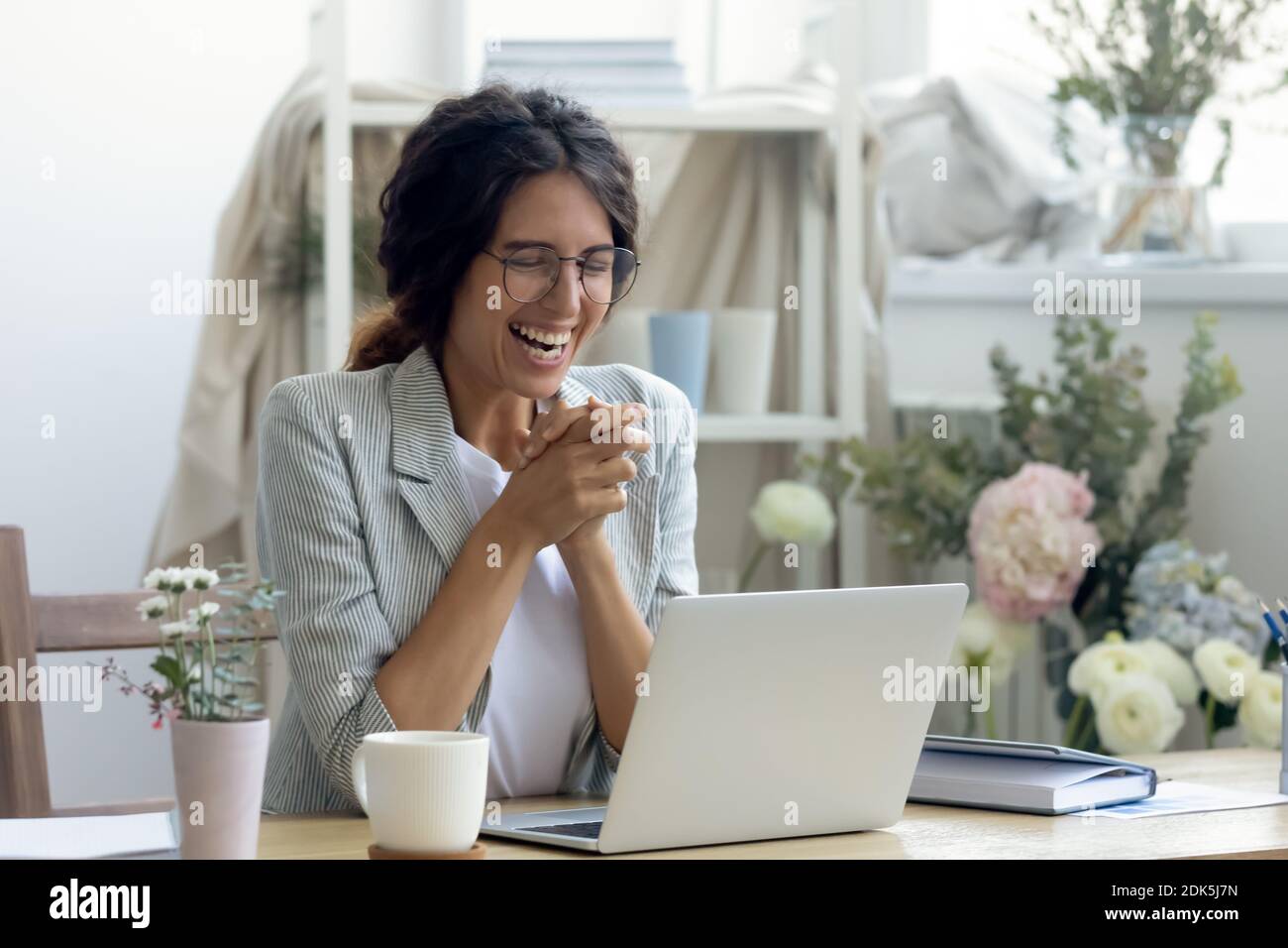 Laughing female enterpreneur decorator reading good news on laptop screen Stock Photo