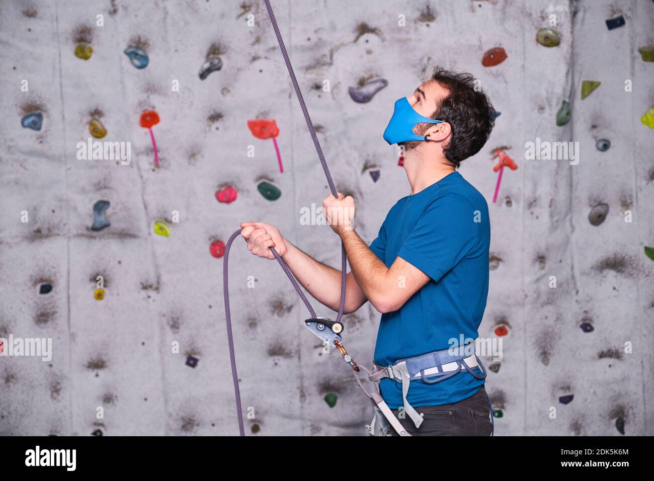Male climber wearing protective face mask securing another climber