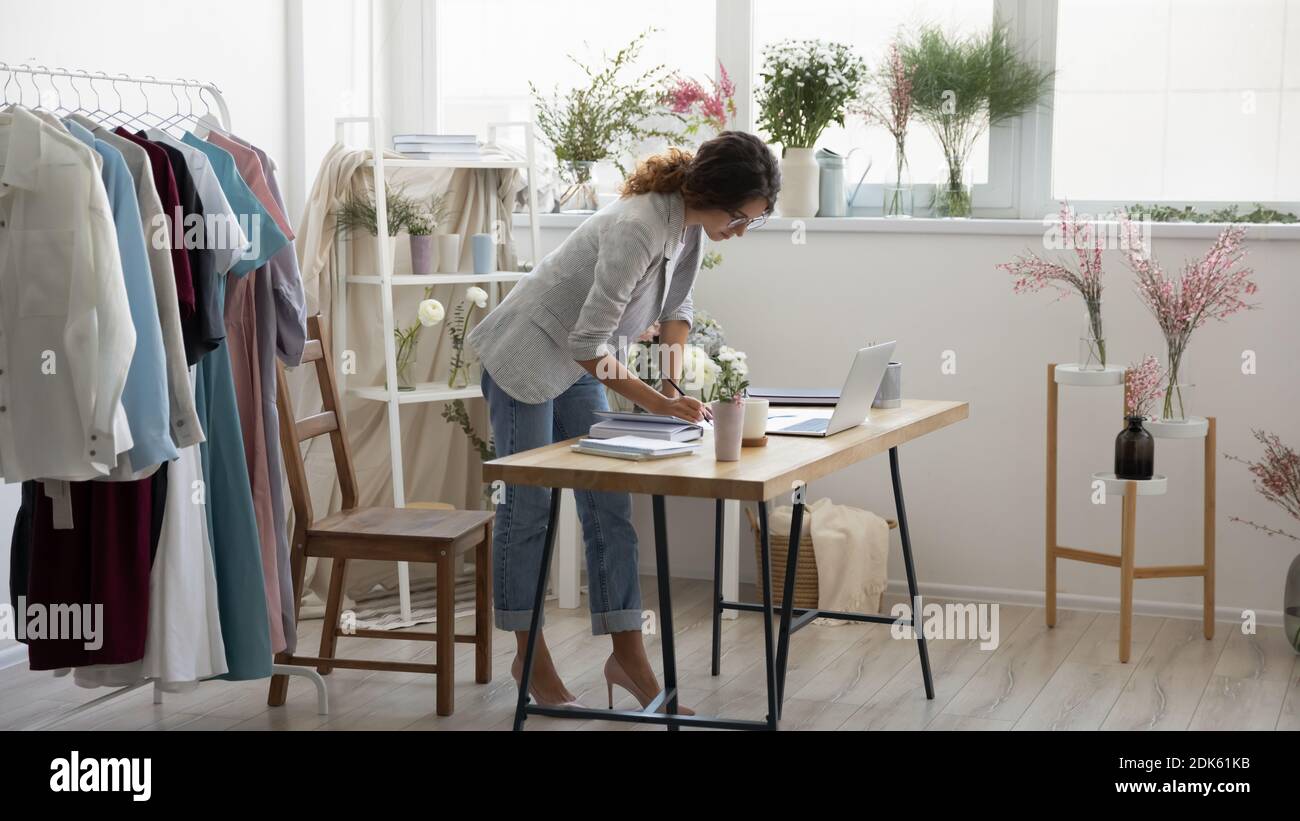 Concentrated young woman decorator standing by desk focused on paperwork Stock Photo