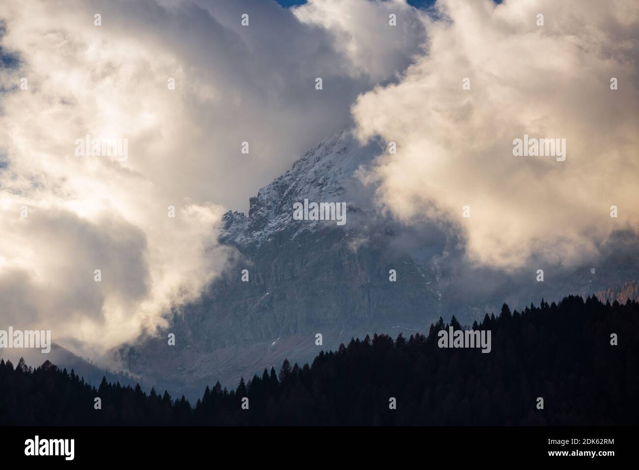 A beautiful view of trees with a rocky mountain under a cloudy sky ...