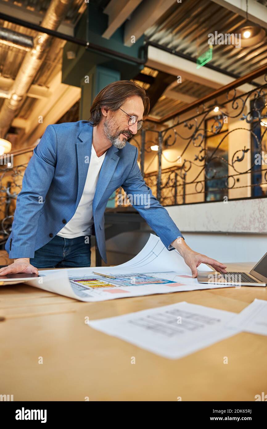 Positive office worker switching on his laptop Stock Photo