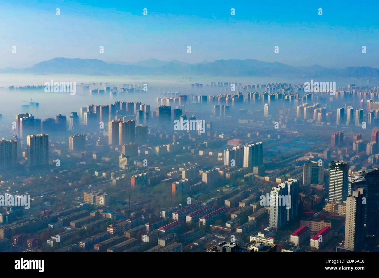The advection clouds flow slowly between the urban buildings, looming like a fairyland in Shijiazhuang city, north China's Hebei province, 12 December Stock Photo