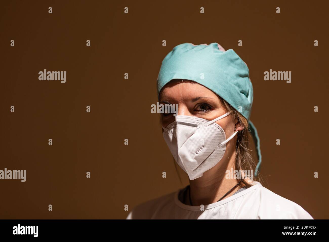 nurse camera look with surgical cyan cap, surgical gown and white mask coronavirus pandemic protection Stock Photo