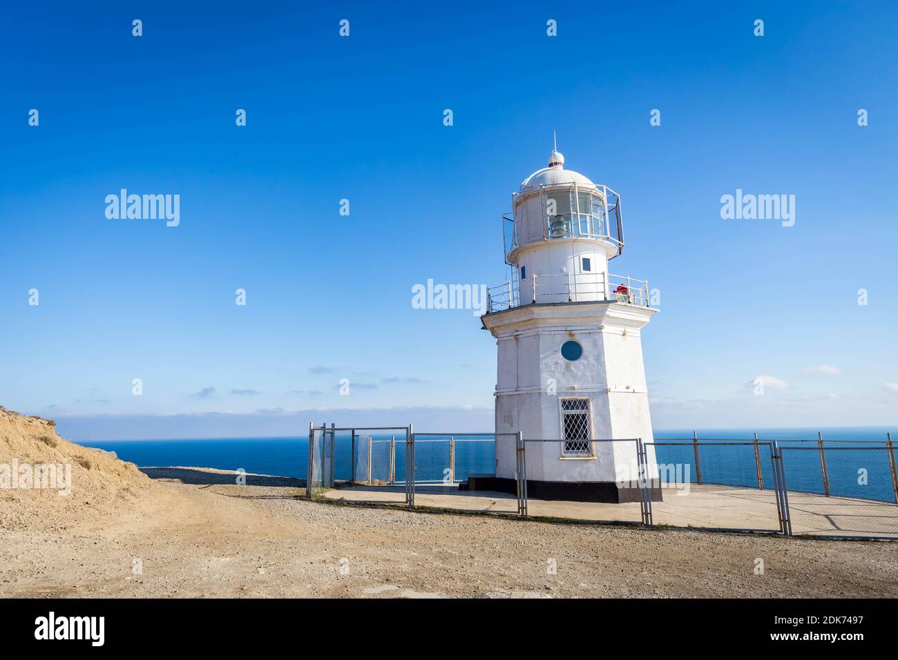 Lighthouse By Sea Against Blue Sky Stock Photo