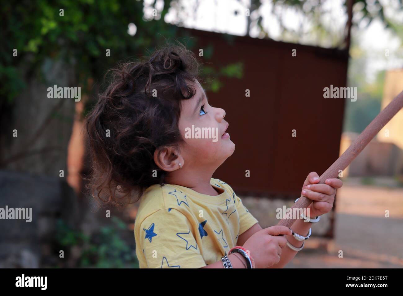 profile view of A little child holding a wooden stick and looking at it Stock Photo