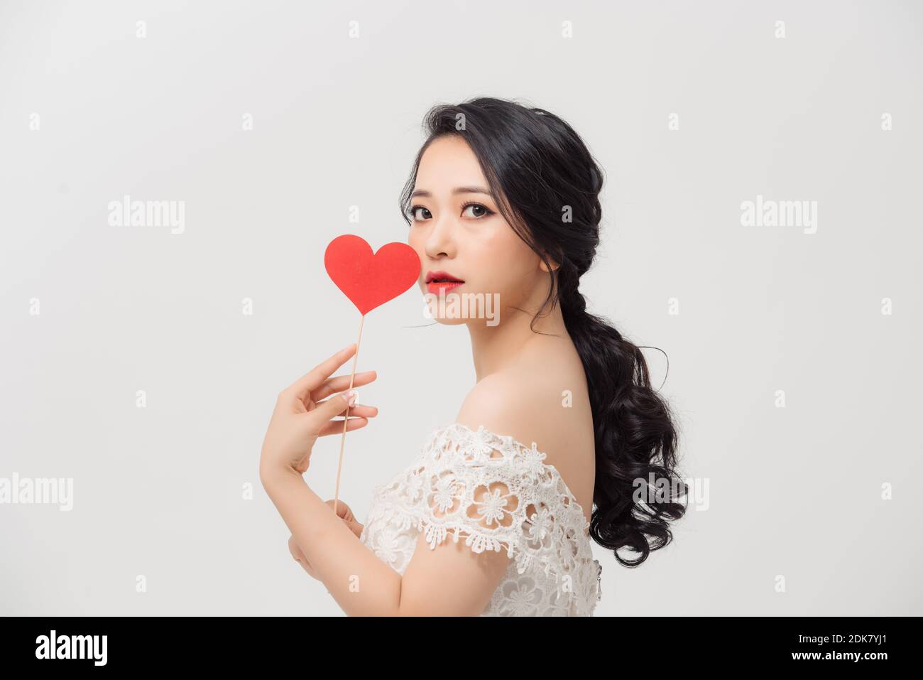 Attractive young Asian woman holding love sign when standing over white ...