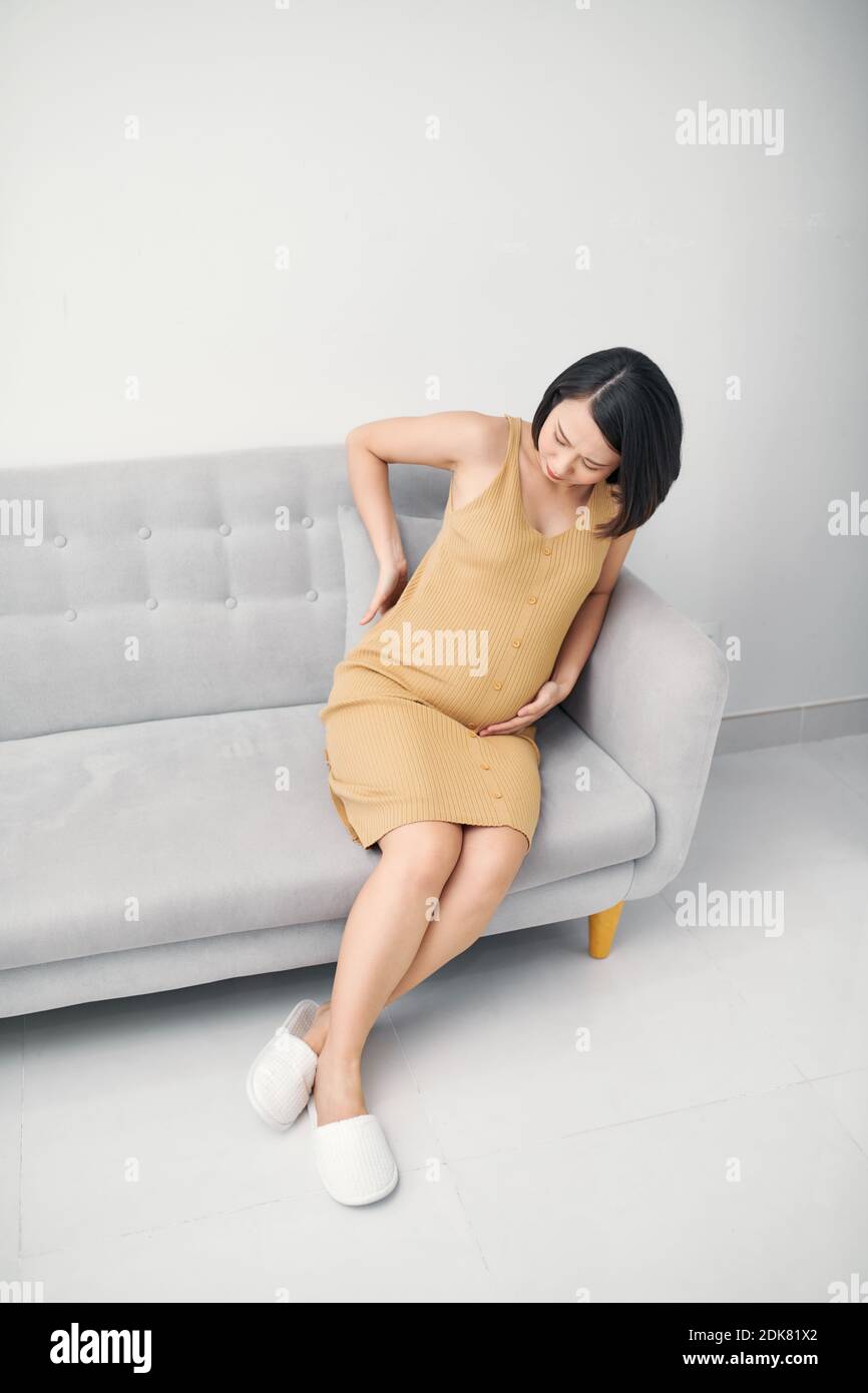 Young pregnant woman suffering from backache at home Stock Photo