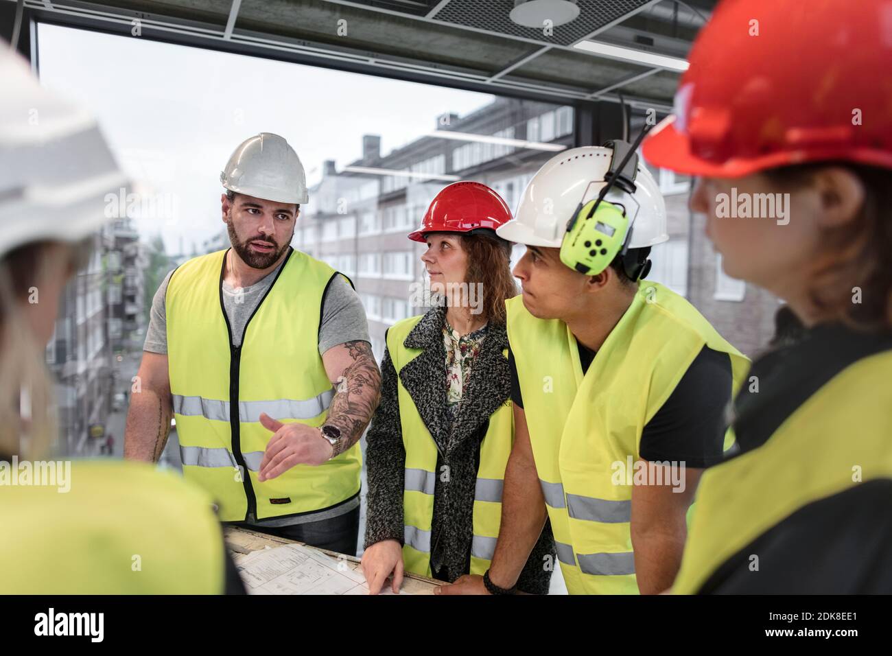 Workers reviewing blueprint at construction site Stock Photo