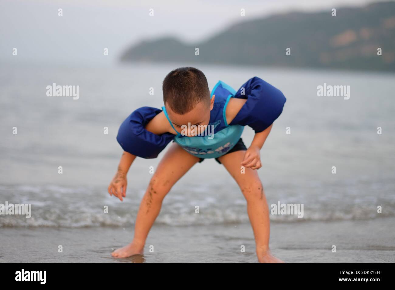 Boy Wearing Water Wings While Playing On Shore At Beach Stock Photo