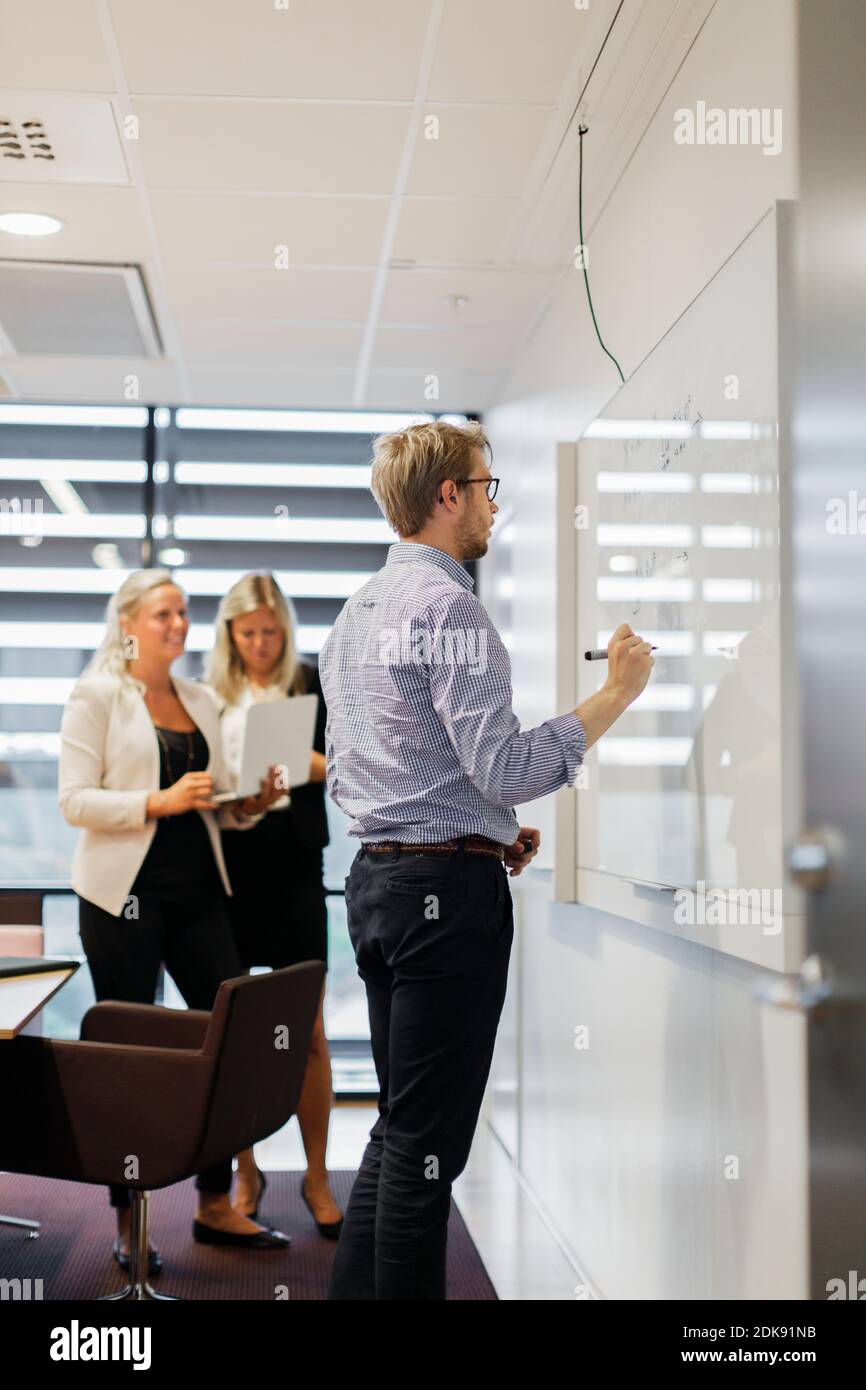 Businessman writing on whiteboard in office Stock Photo