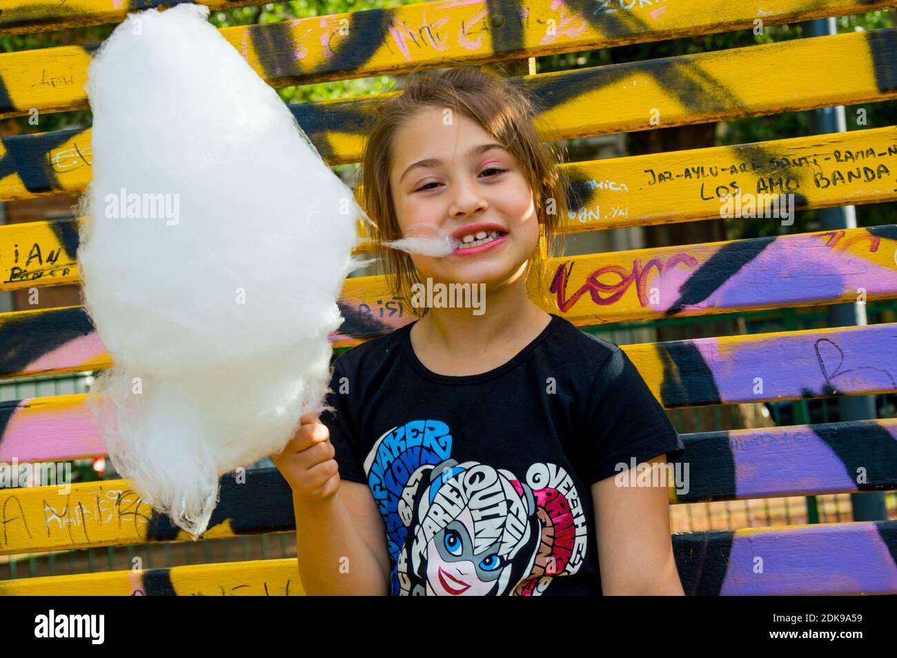 Portrait Of Girl Eating Cotton Candy While Standing Outdoors Stock Photo