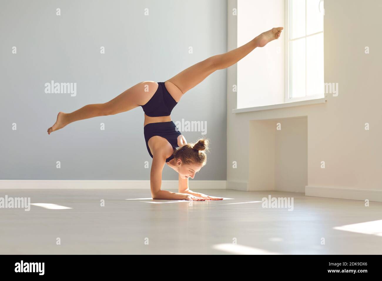 Young female gymnast doing arm stand while practicing gymnastics in