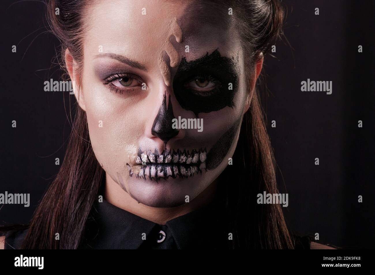Close-up Portrait Of Young Woman With Spooky Make-up Against Black Background Stock Photo