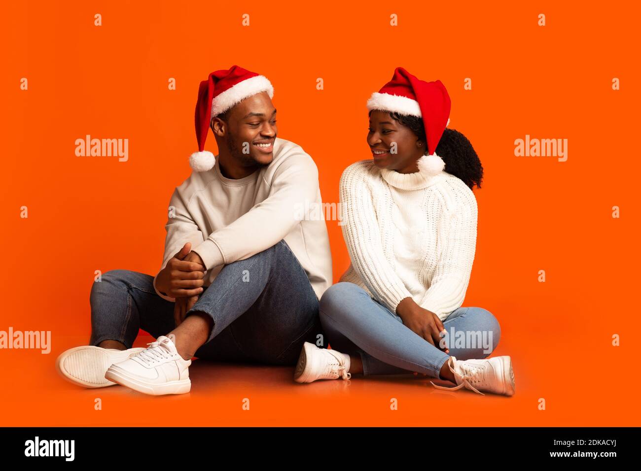 Positive Black Man And Woman In Santa Hats Smiling To Each Other Stock ...