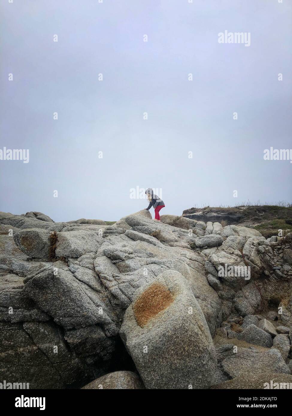 Girl On Rock Formation Against Sky Stock Photo