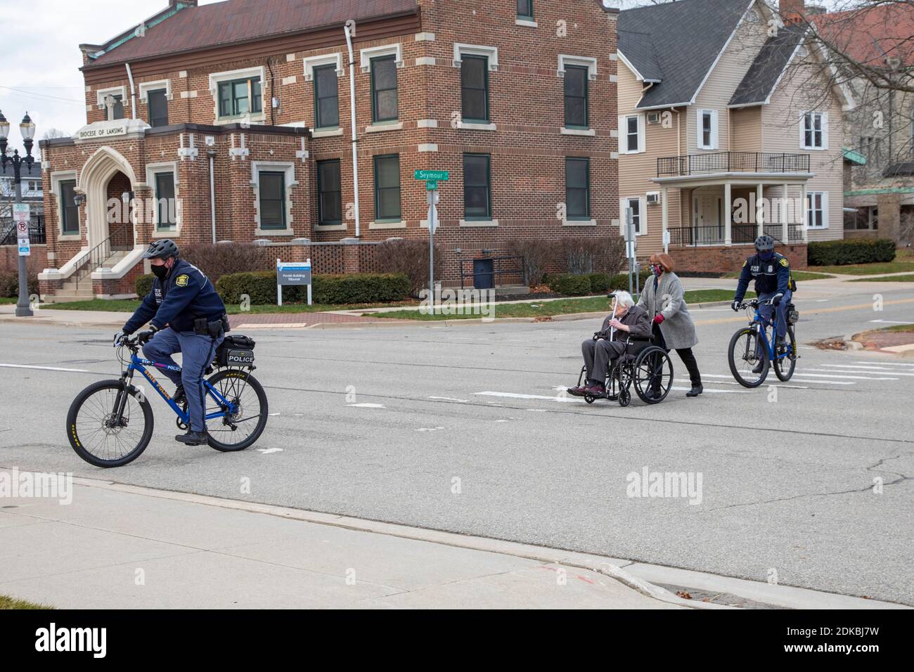 Lansing, Michigan, USA. 14th Dec, 2020. As the Electoral College prepares to meet, elector Mike Kerwin (in wheelchair) is guarded by state police as he arrives at the Michigan state capitol to cast his vote for Joe Biden. Kerwin, a long-time United Auto Workers activist, is pushed by his daughter, Katie Kerwin. Credit: Jim West/Alamy Live News Stock Photo