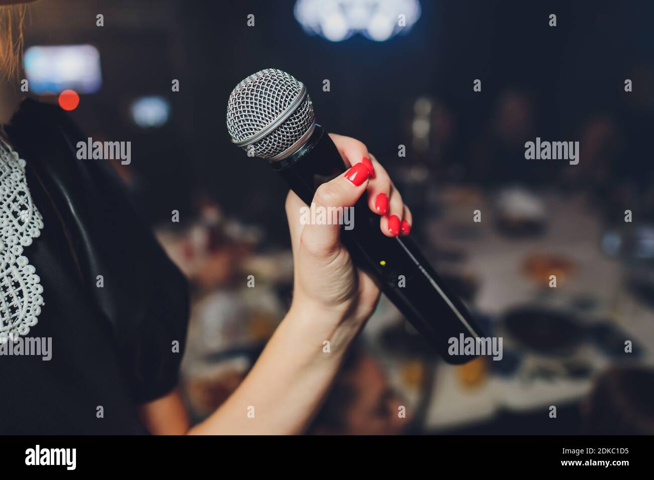 Microphone and unrecognizable female singer close up. Cropped image of  female singer in pink dress , singing into a microphone, holding mic with  two h Stock Photo - Alamy