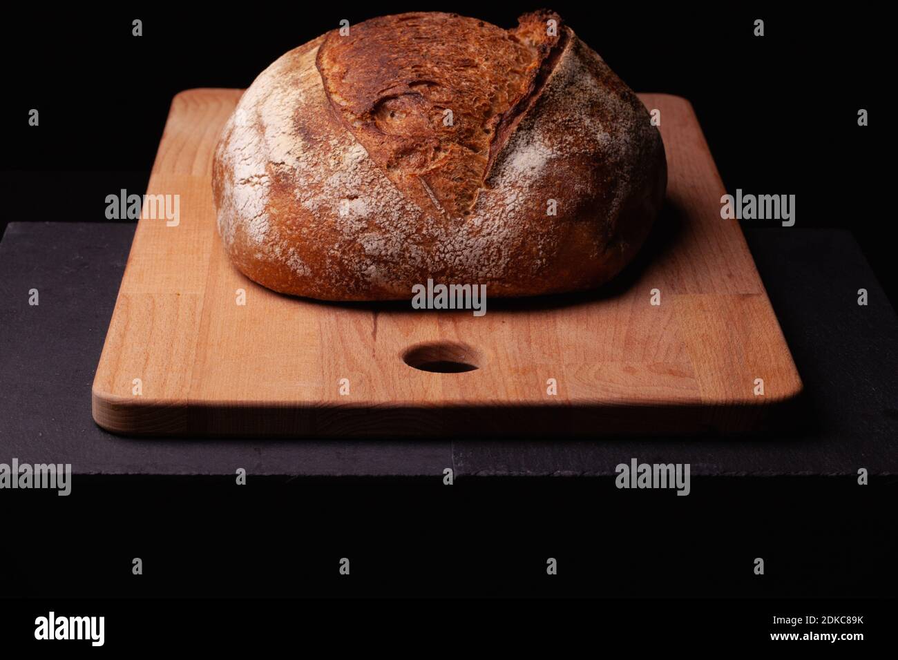 Artisan sourdough bread. Freshly baked round loaf of sourdough bread on black background. Stock Photo