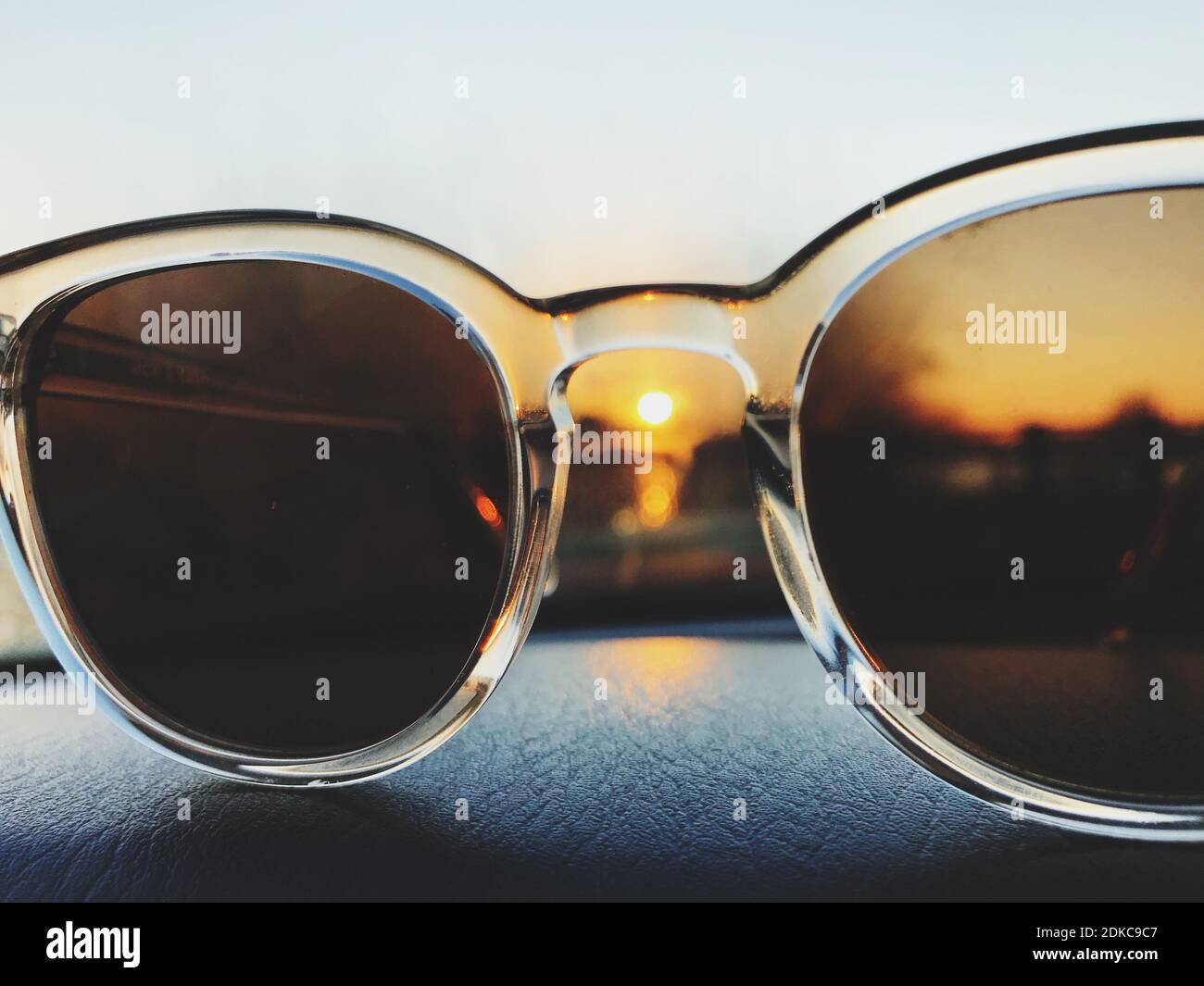 Closeup Of Sunglasses On Dashboard In Car During Sunset Stock Photo