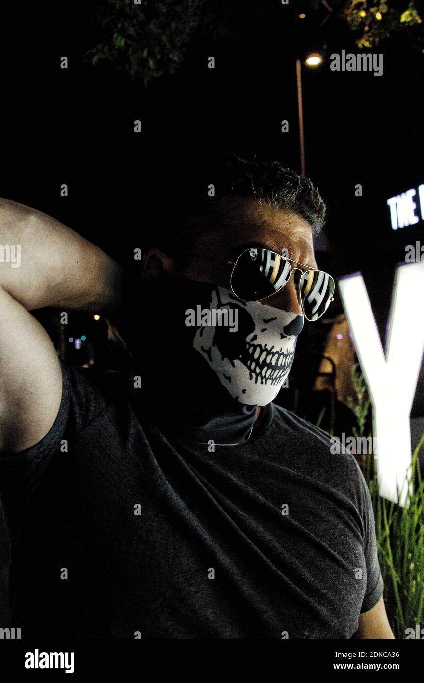 Close-up Of Man Wearing Sunglasses And Skull Mask At Night Stock Photo