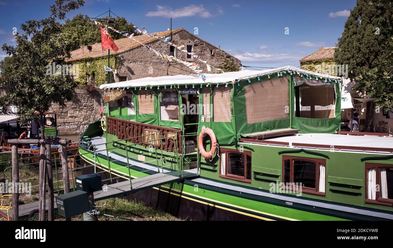 The Péniche Tamata was built in 1924. The boat is 24 meters long and has been converted into a grocery store. It is located in the Canal du Midi in Le Somail. The Canal is a UNESCO World Heritage Site and was completed in 1681. It was designed by Pierre Paul Riquet. Stock Photo