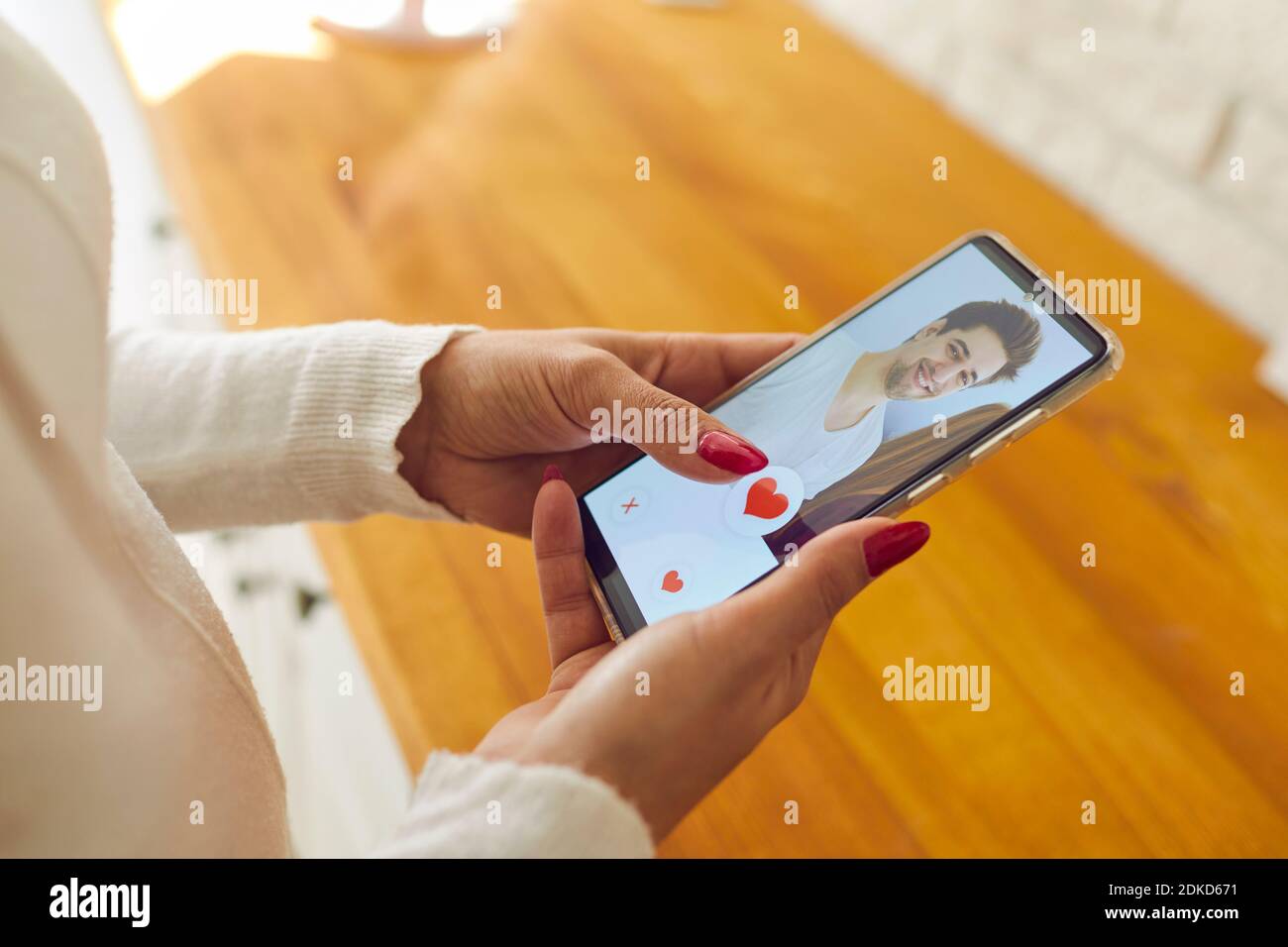 Single woman holding mobile and giving like to man's profile picture on dating app Stock Photo