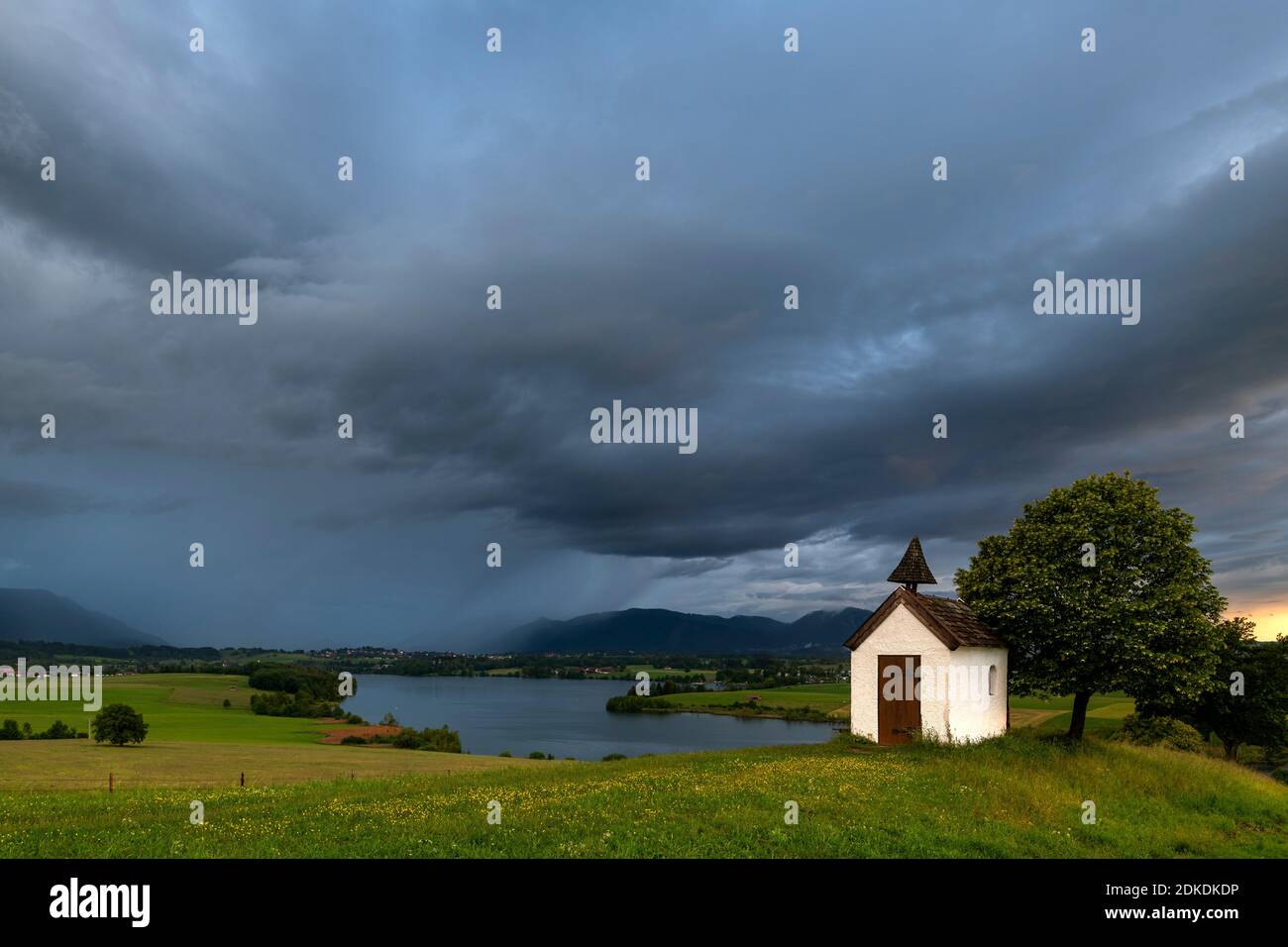Rain Towers Near Me Storm During Sunset At The Riegsee, In The Background The German Alps Of  The Karwendel, Estergebirge And The Ammergau Alps - With Dark Storm Clouds  And Rain Veils, As Well As A