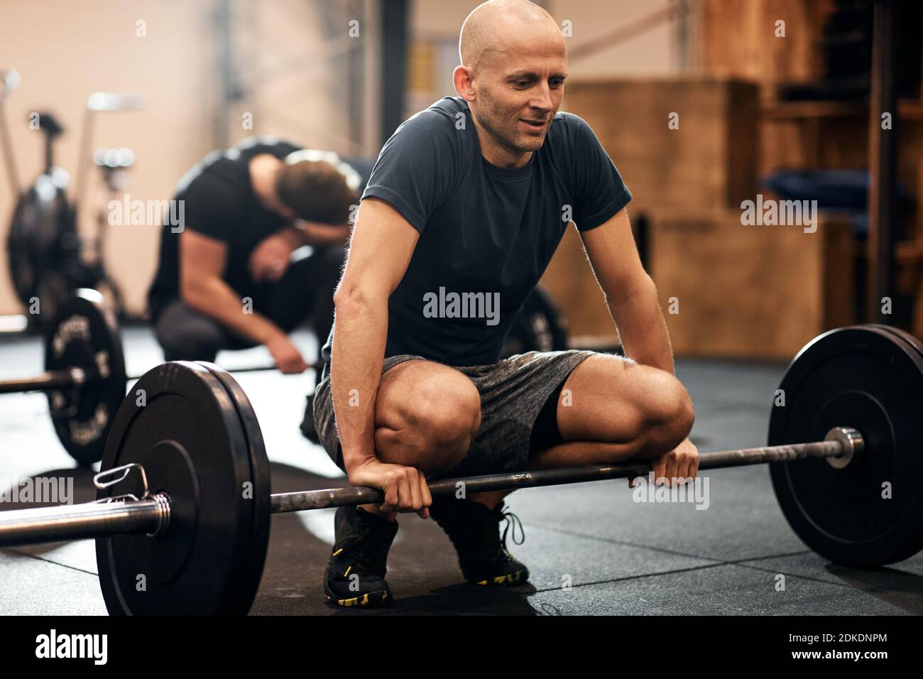 Fit man in sportswear getting ready to lift heavy weights during a strength training class a the gym Stock Photo