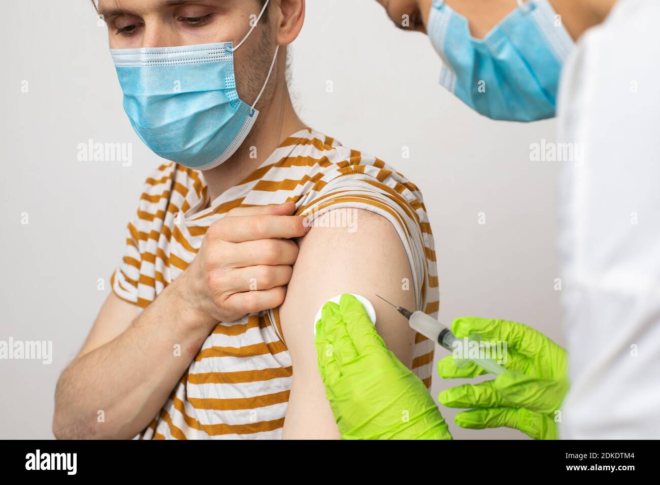 Man receives jab, male getting vaccinated. Parents gets a shot Doctors set to give first authorized doses of Covid-19 vaccine Second-Generation Stock Photo