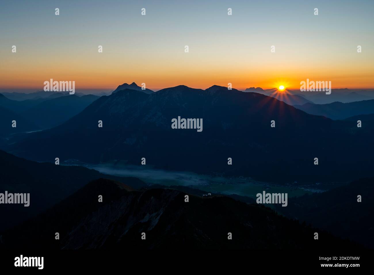 Sonnenstern am Unnütz and Guffert, above Lake Achensee, in the Achenkirch valley in Tyrol, shrouded in darkness, photographed from the Karwendel mountain range under a blue sky. Stock Photo