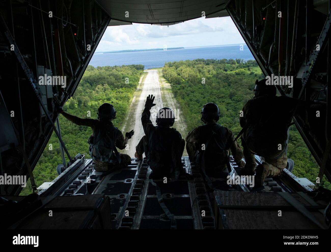 U.S. Air Force Brig. Gen. Jeremy T. Sloane, 36th Wing commander, center left, and 36th Airlift Squadron loadmasters, wave after airdropping bundles of donated goods during Operation Christmas Drop 2020 December 7, 2020 onto Angaur, Republic of Palau. Operation Christmas is the longest-running humanitarian airlift operation begun in 1952 to assist remote islanders scattered across 50 islands in the Pacific. Stock Photo