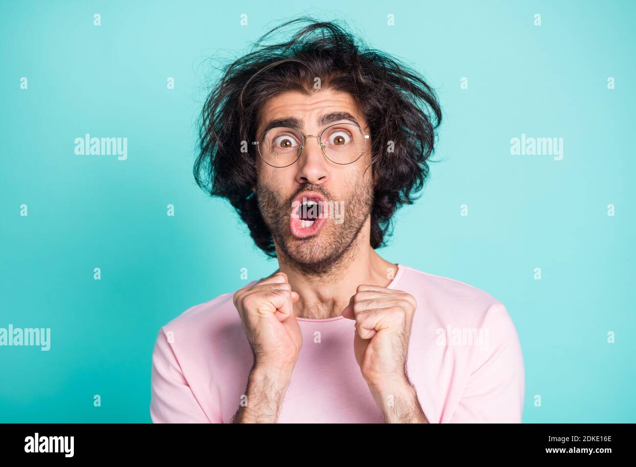 Close up portrait of shocked weird hairdo person fists up yell open mouth isolated on turquoise color background Stock Photo