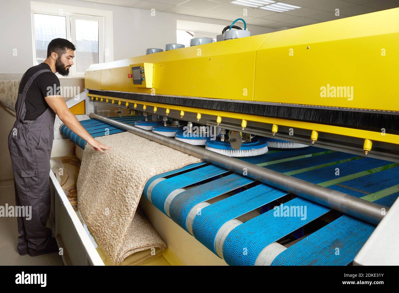 Man operating carpet automatic washing machine in professional laundry service Stock Photo