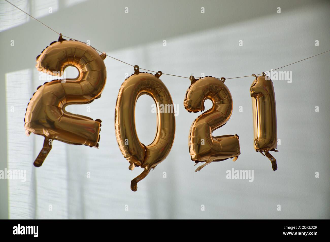 New year's 2021 balloons handing on string indoors. White wall background. Stock Photo