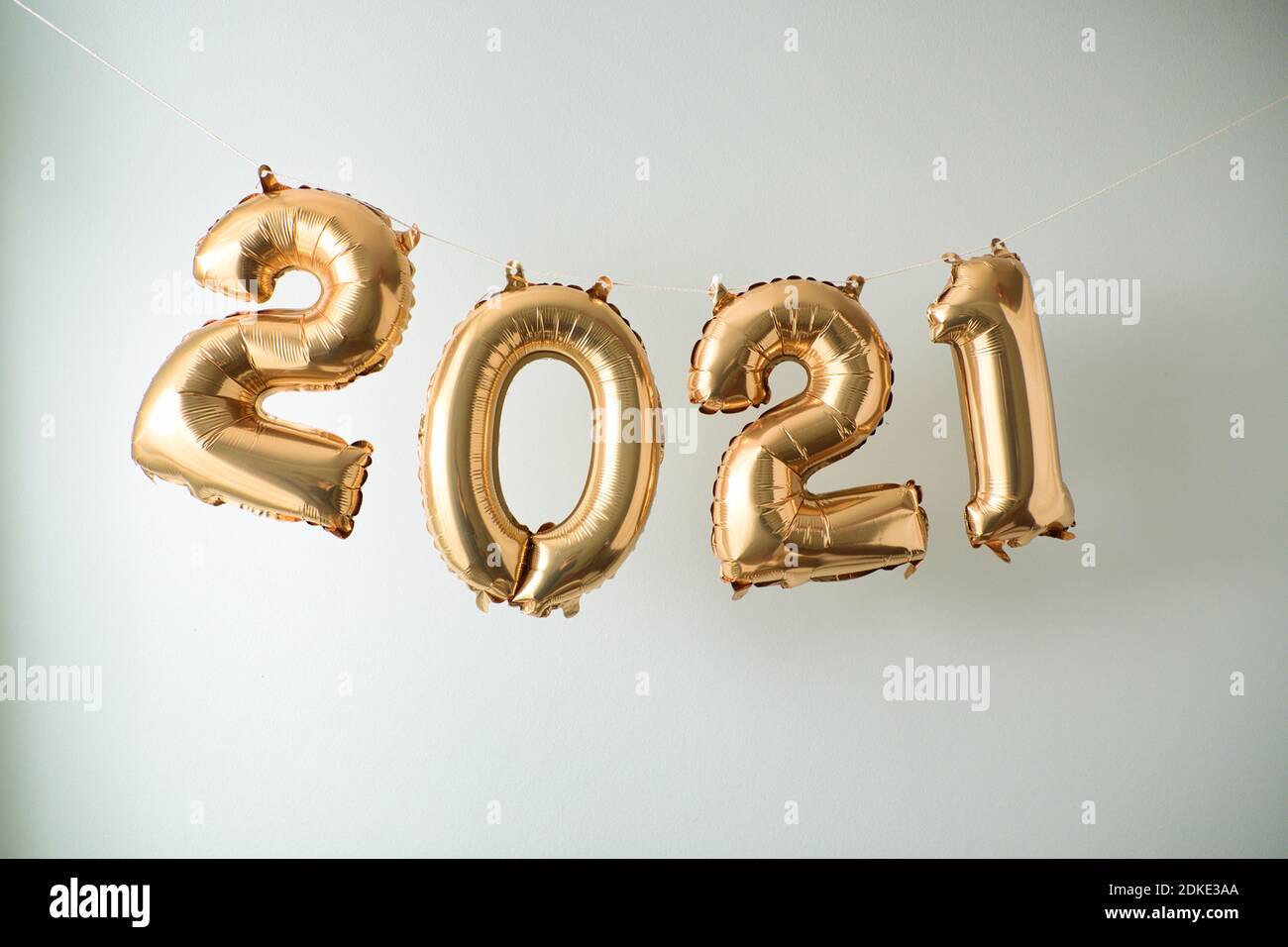 Inflated New Year's balloon numbers hanging in front of white wall background. Stock Photo