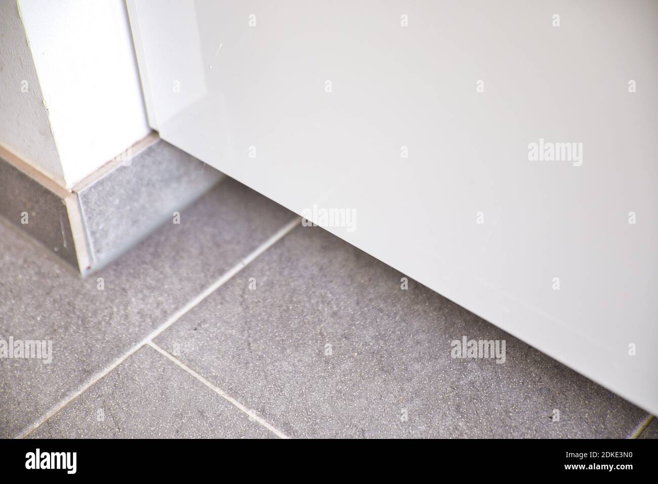 Floor tiles of home corner and metal refrigerator door. High angle view. Stock Photo