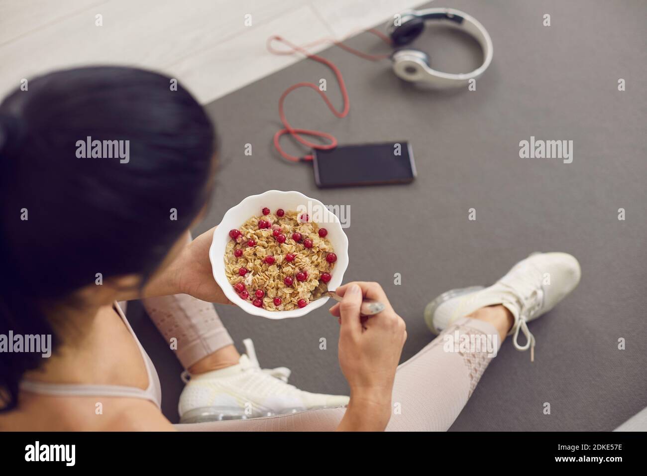 Top view of a bowl of oatmeal with cranberries in the hands of an unknown sports woman. Stock Photo