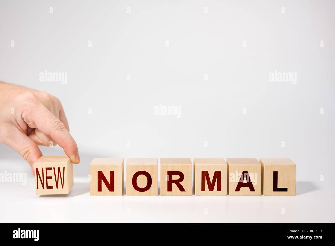 hand arranging wooden cubes with NEW NORMAL word. Adapting to new life or business post-lockdown coronavirus pandemic. Business with social distancing Stock Photo