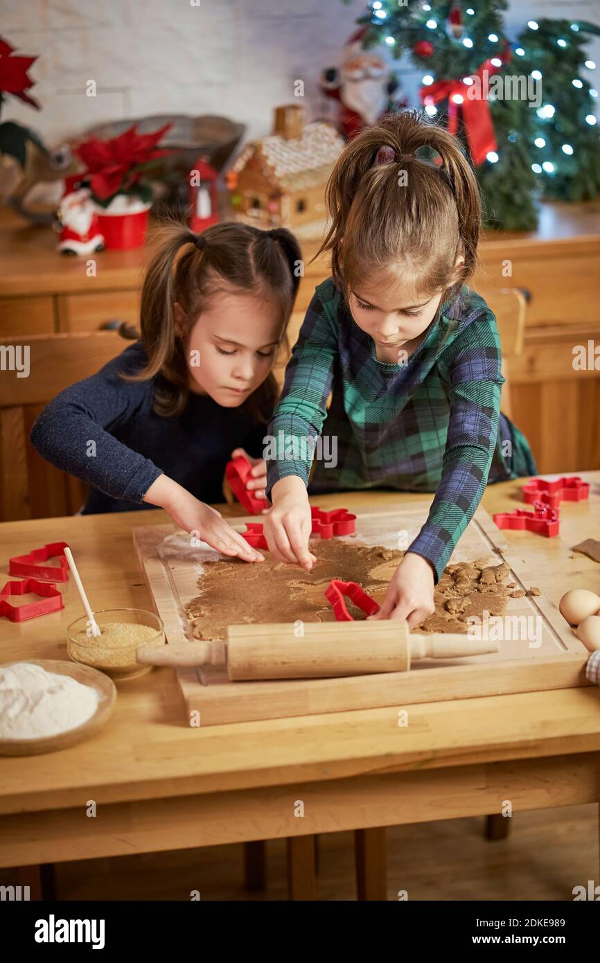two cute sisters make and decorate Christmas gingerbread cookies Stock Photo