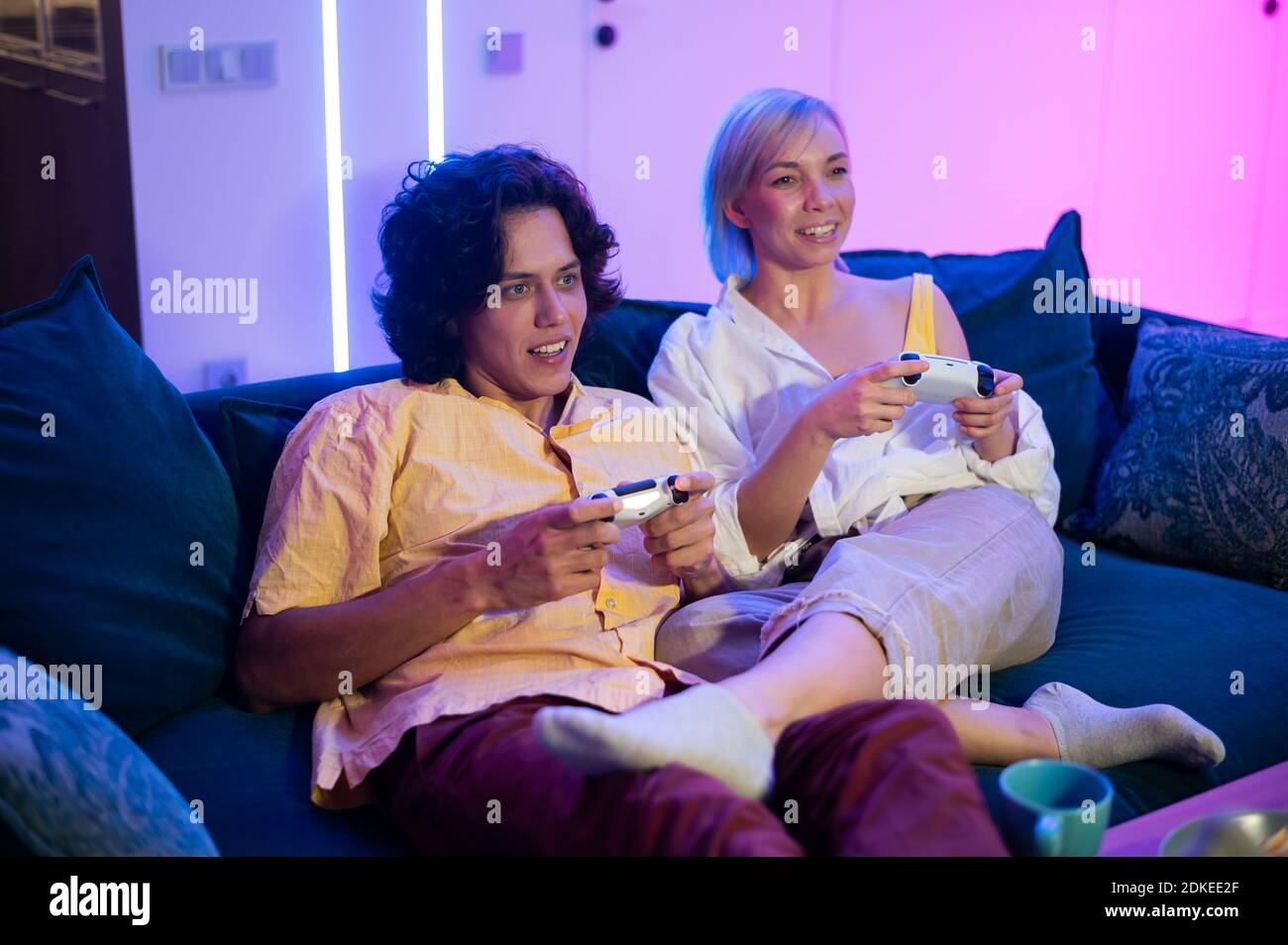 Happy boyfriend and girlfriend playing video games and holding