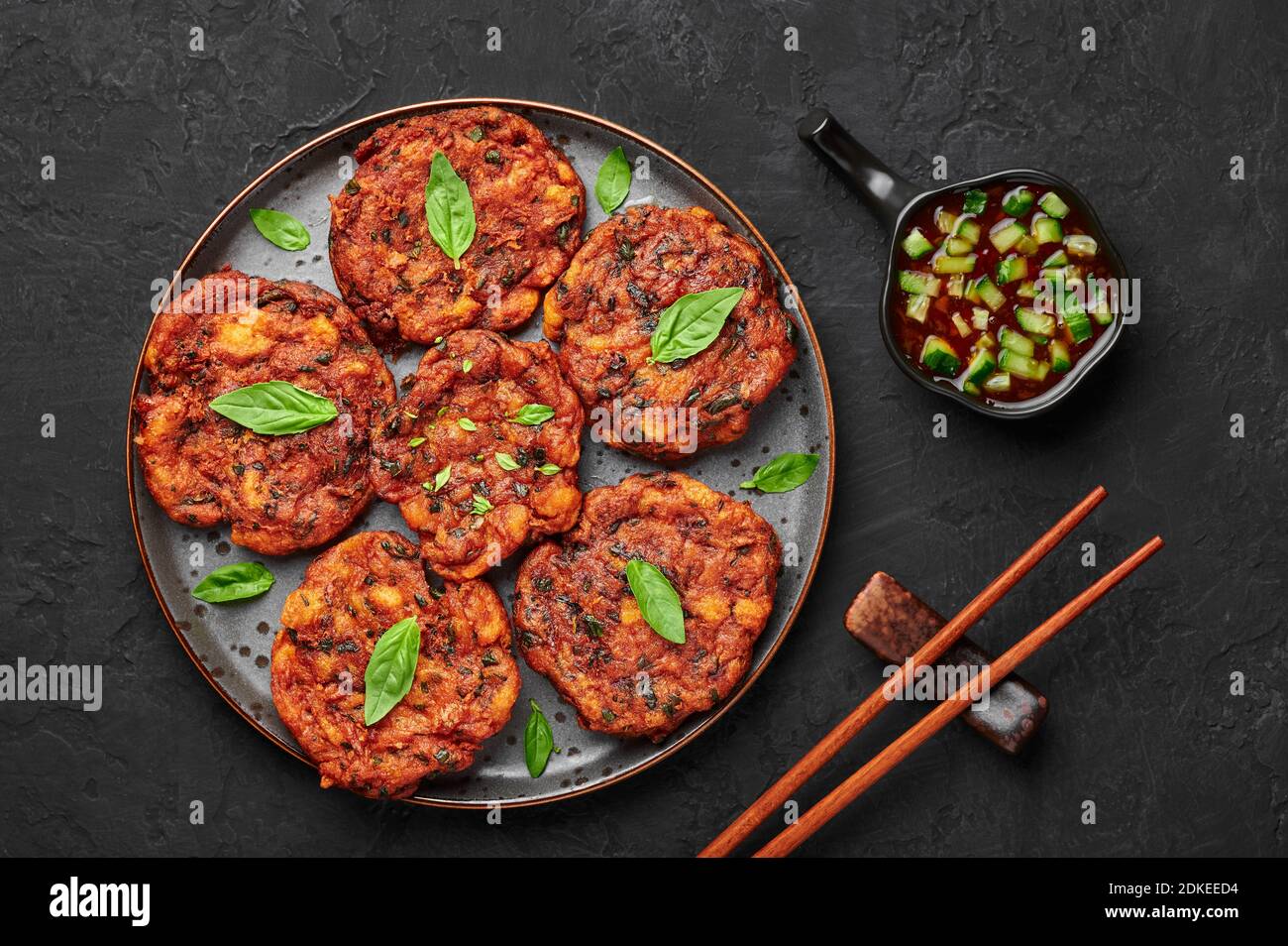 Tod Mun Pla or Thai Fish Cakes on black plate on dark slate table top. Traditional Thailand cuisine dish. Asian food and meal. Top view Stock Photo