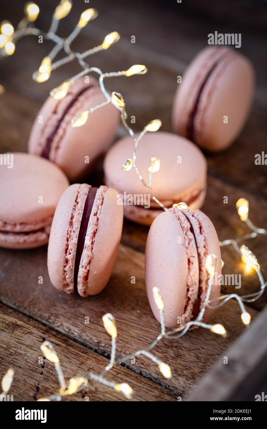 Fig macarons beautifully arranged on a wooden plate , winterly decorated with fir branches and pine cones, a LIchter chain glows in the background Stock Photo