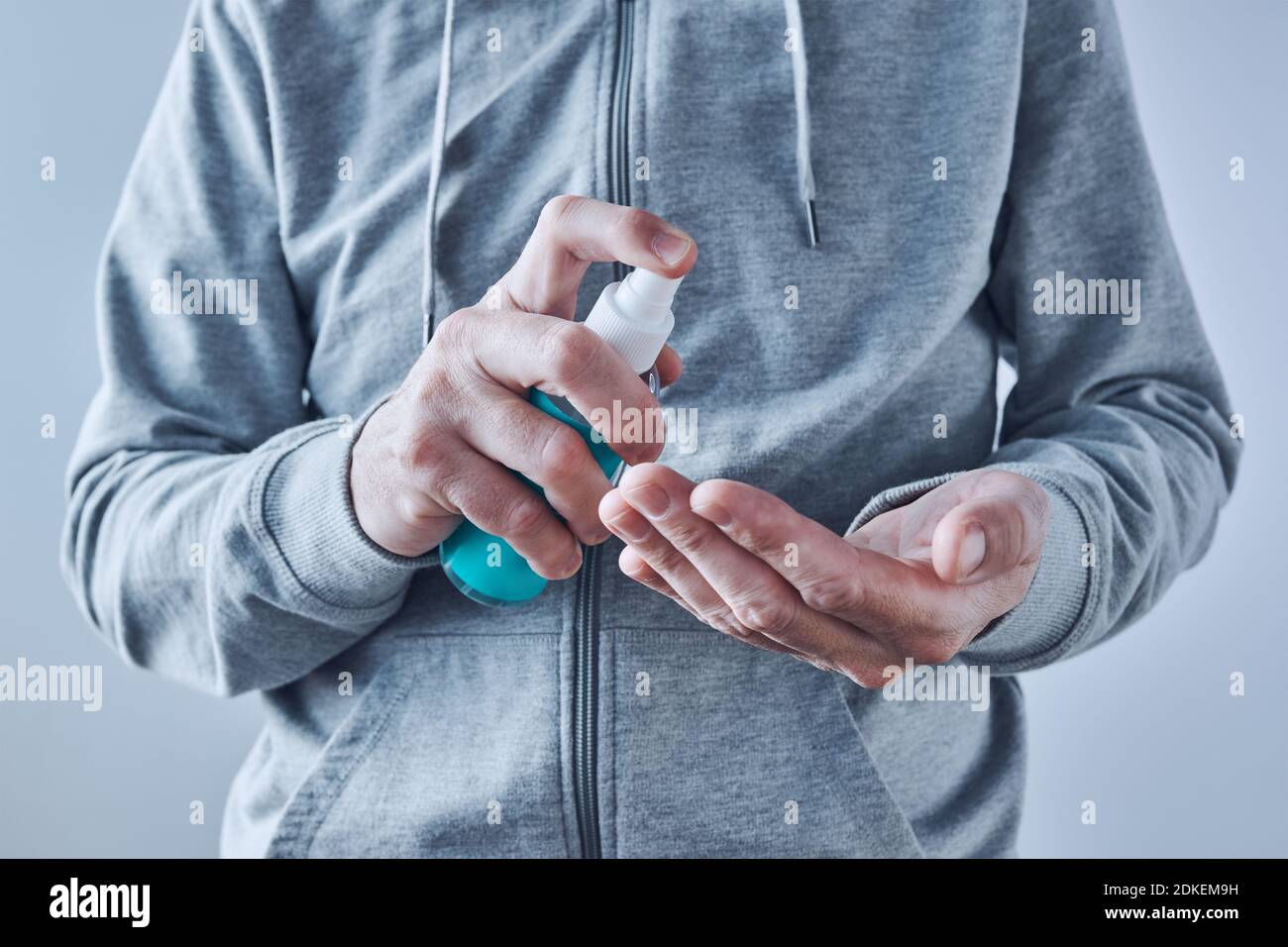 Hands disinfecting with sanitizer spray, close up with selective focus Stock Photo