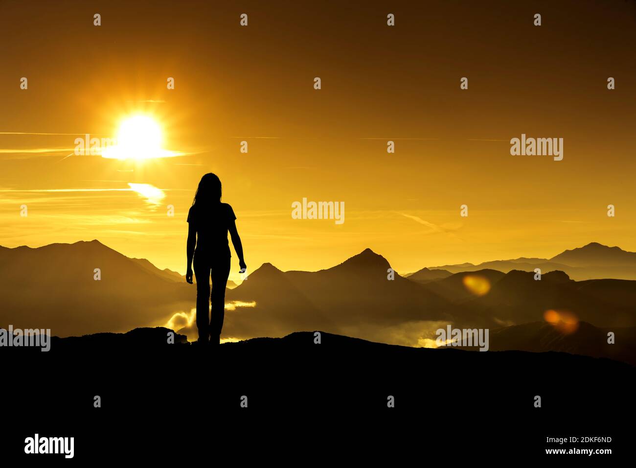 Woman looks at a sunrise in the mountains Stock Photo