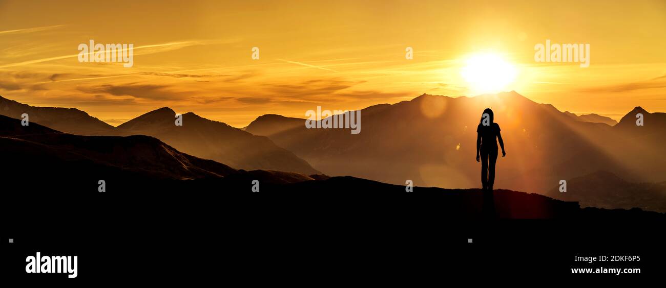 Woman looks at a sunrise in the mountains Stock Photo