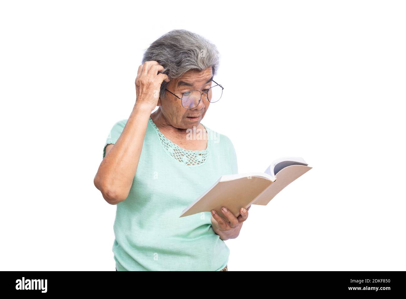 Senior Woman Wearing Eyeglasses Reading Book Against White Background Stock Photo