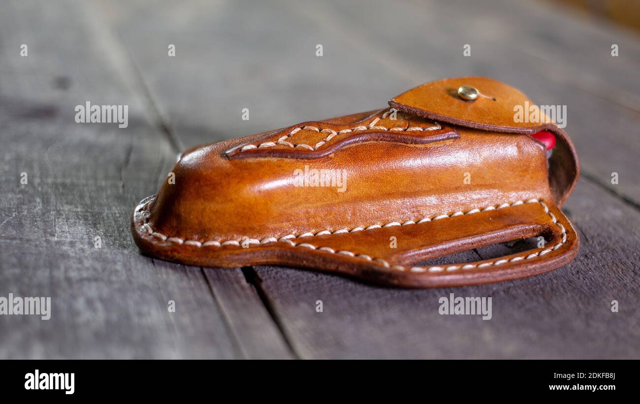 Handmade Leather Pancake Knife Sheath on wooden background. Stitching