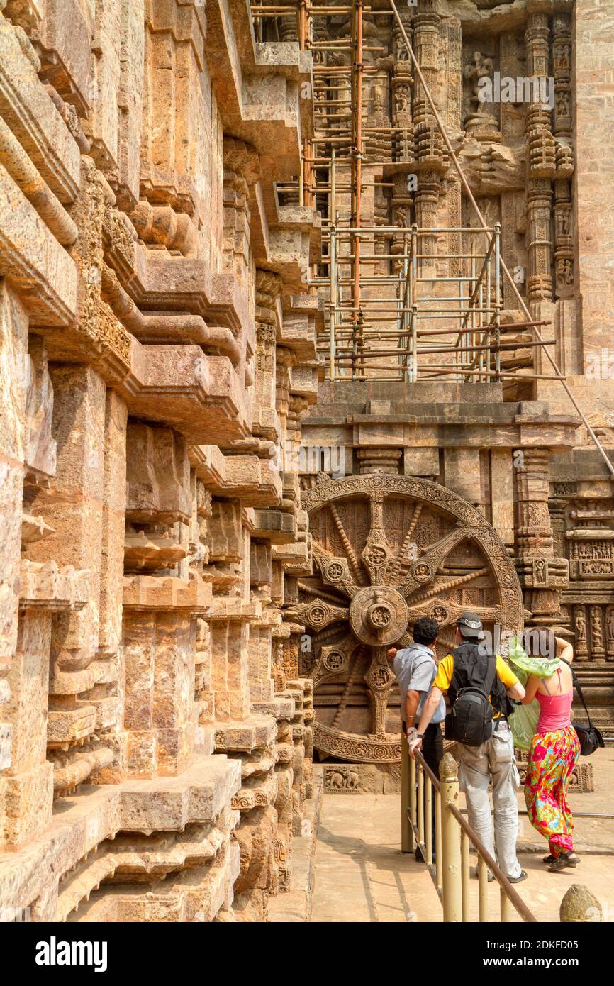 Konark, India – March 14, 2012: Tourists visiting the sights - chariot wheel intricate splendid carvings in the ancient Hindu Sun Temple. 13th-century Stock Photo