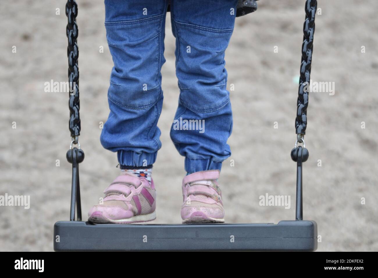 Low Section Of Girl Standing On Swing Stock Photo